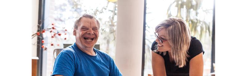 Male with a learning disability with his worker. Both are smiling.